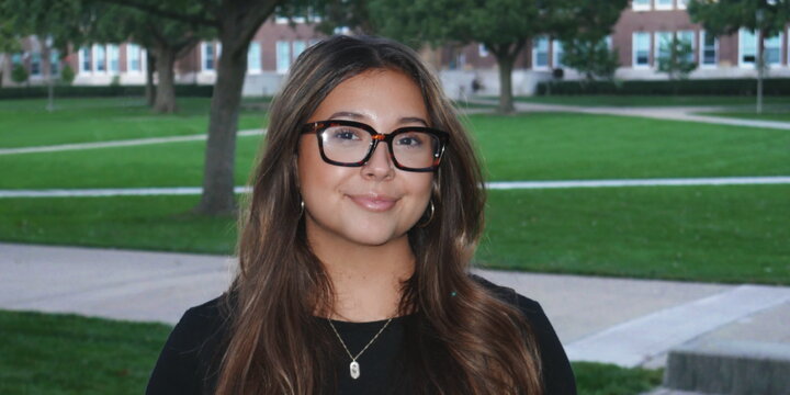A photo of Jazmin Olivas standing on the quad and smiling at the camera