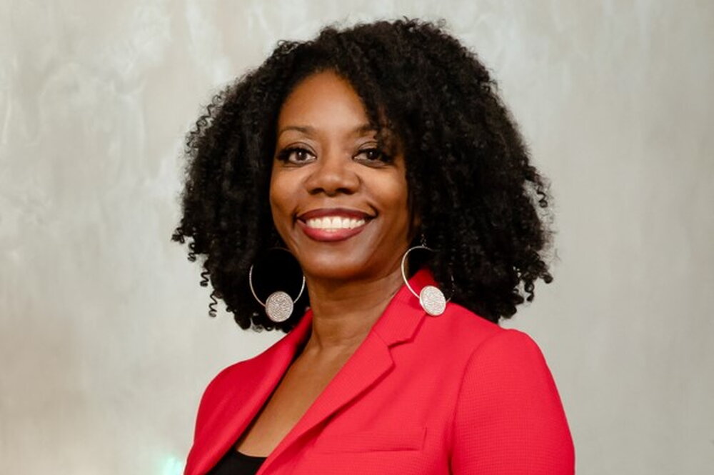 A photo of Dr. Ruby Mendenhall. She is smiling at the camera and wearing a red jacket.