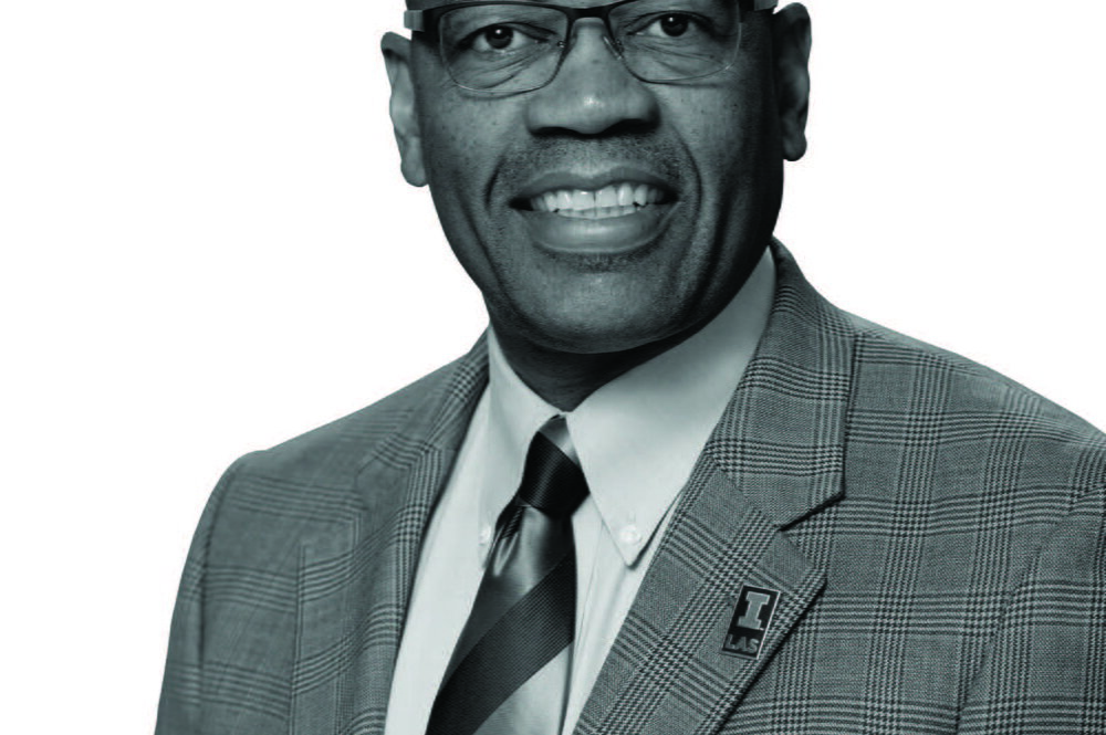A black-and-white image of Reuben May smiling at the camera.