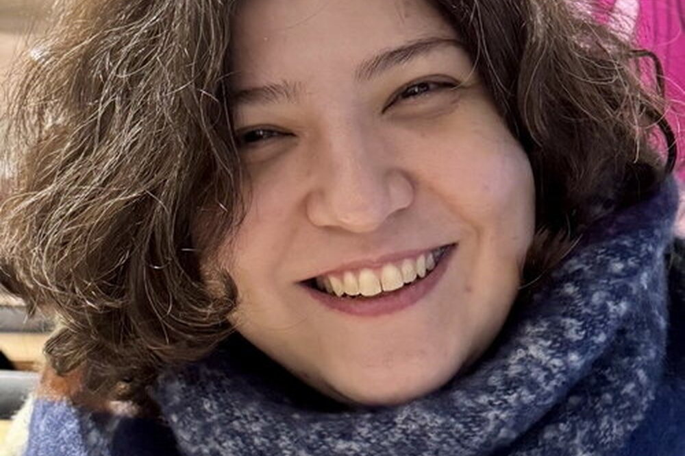 Soodeh Mansouri wears a colorful knit scarf and smiles at the viewer.
