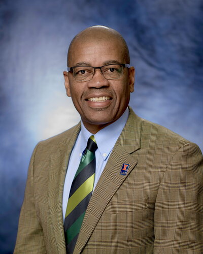 Reuben May wearing a suit and smiling at the camera.