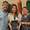 Jazmin Olivas stands between her parents, holding an award.