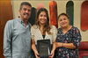 Jazmin Olivas stands between her parents, holding an award.