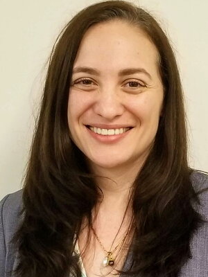 Loren Henderson smiling at the camera. She has long dark hair and wears a gray suit.